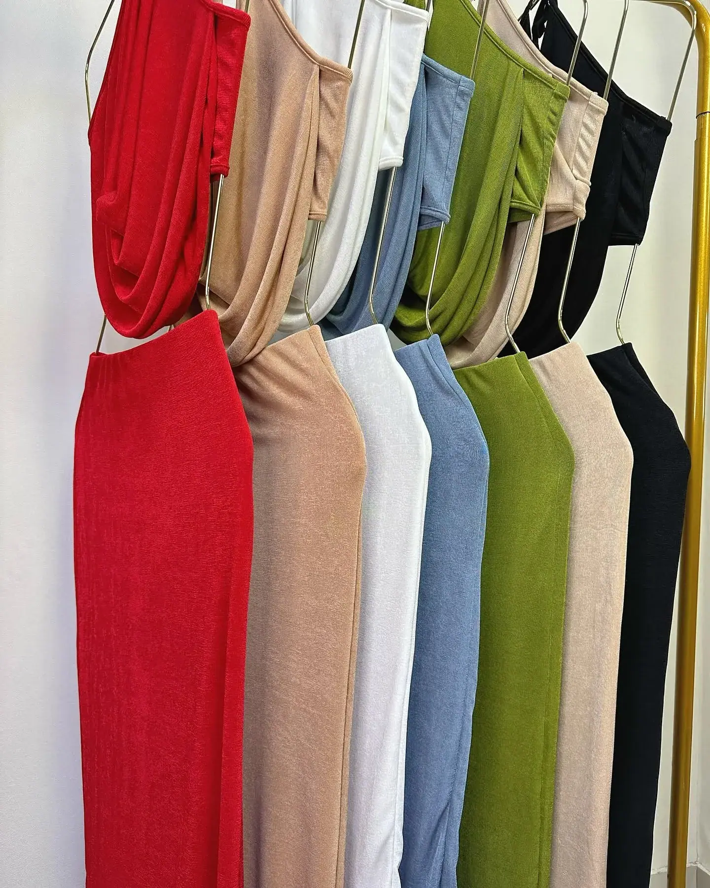 Conjuntos drapeados colgados en siete colores: rojo, camel, blanco, celeste, oliva, beige y negro
