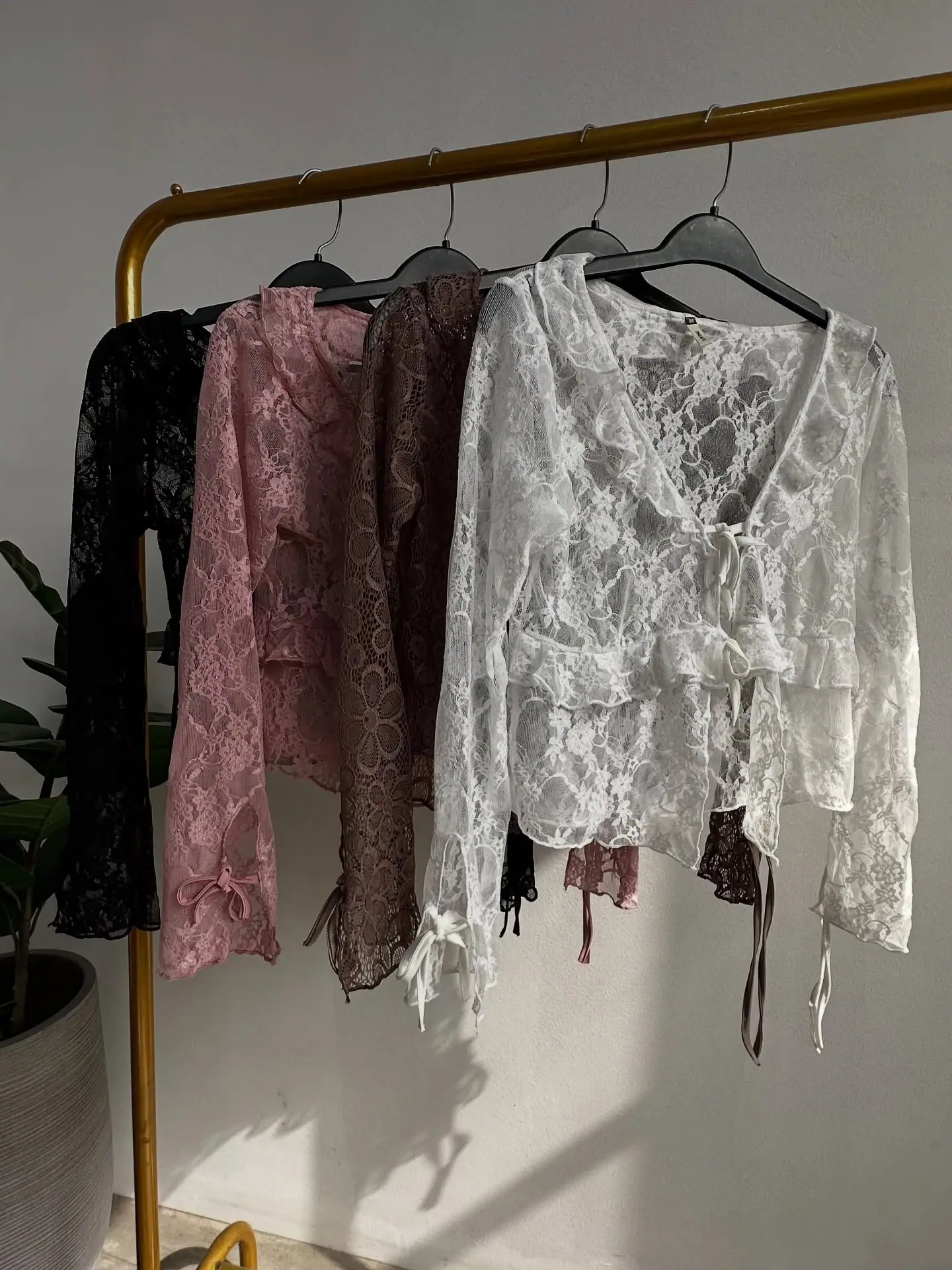Cuatro tops de encaje con lazos colgados: negro, rosa, marrón y blanco