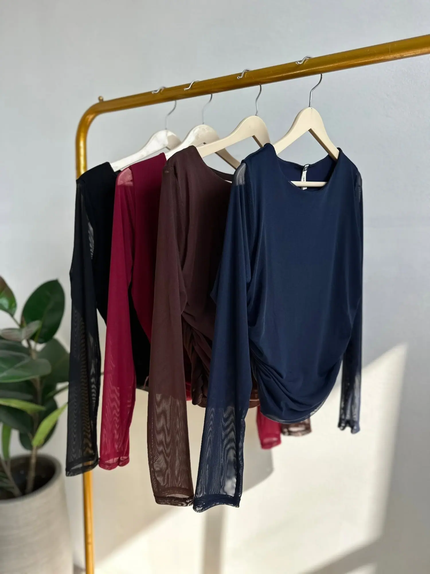 Cuatro tops de malla de manga larga colgados: negro, vino, chocolate y azul marino
